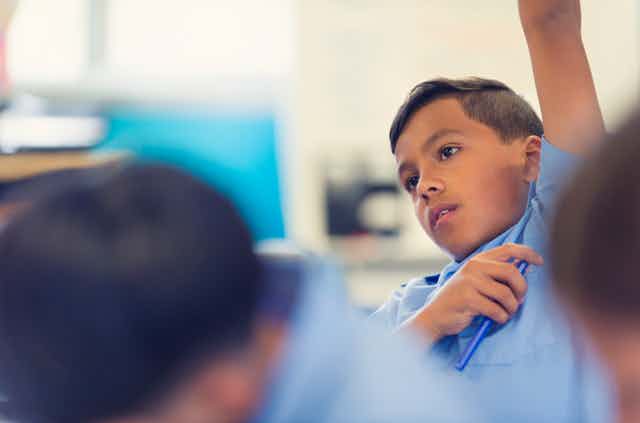 A boy raises his arm in a classroom