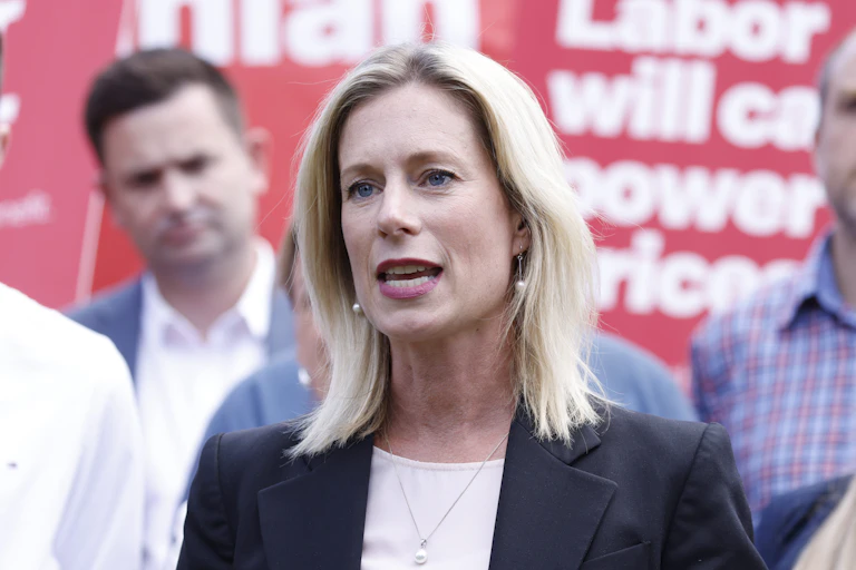 A woman gives a speech at a press conference in front of red signage