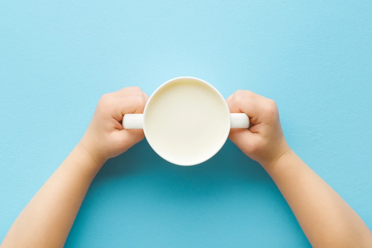 Child holding sippy cup of milk
