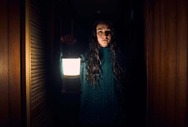 A young woman holds up a lamp,