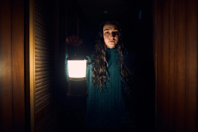 A young woman holds up a lamp,