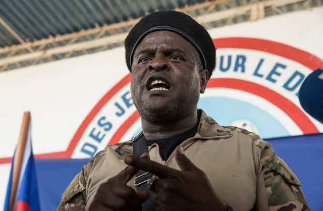 A close-up shot of a man wearing a hat delivering a speech.