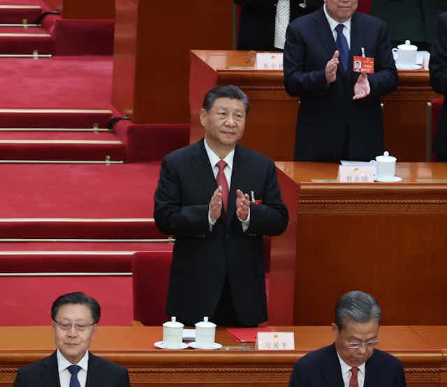 Xi Jinping stood beside a desk clapping.