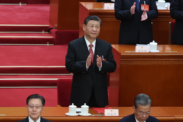 Xi Jinping stood beside a desk clapping.