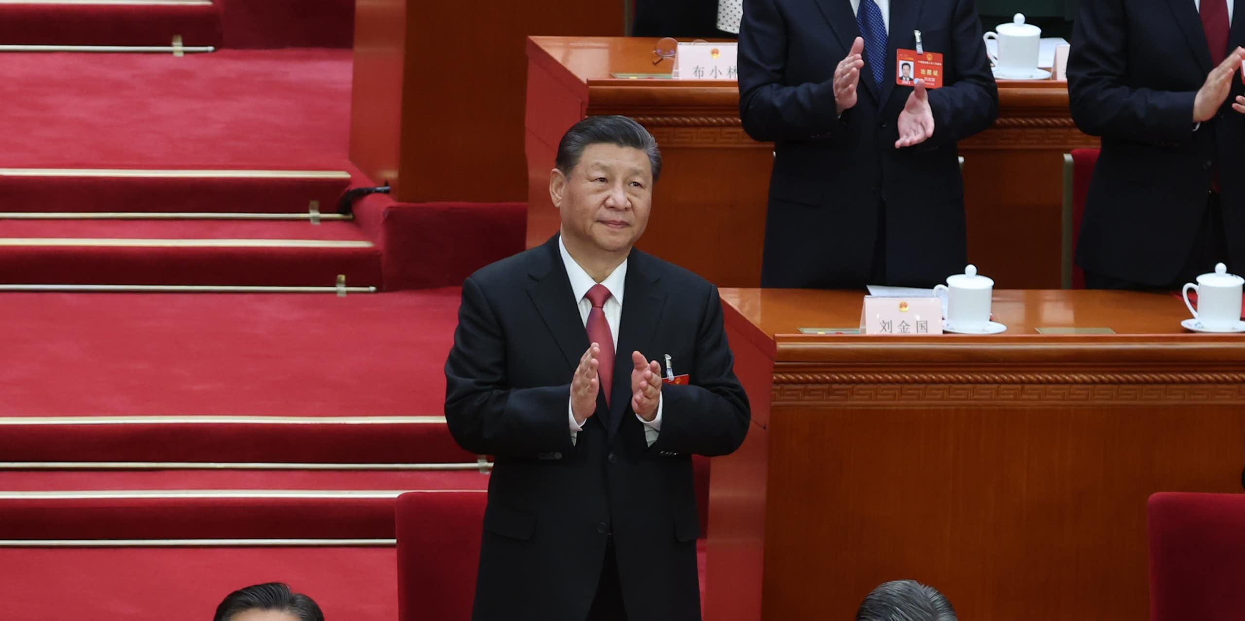 Xi Jinping stood beside a desk clapping.