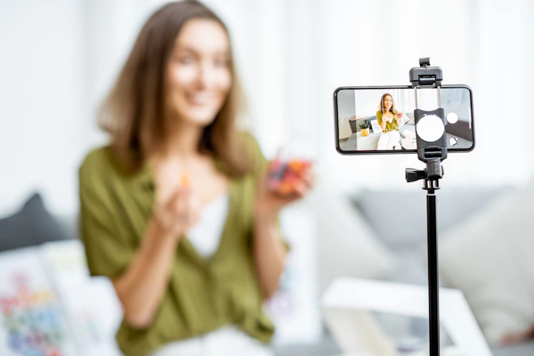 A woman out of focus recording video on a smartphone in the foreground