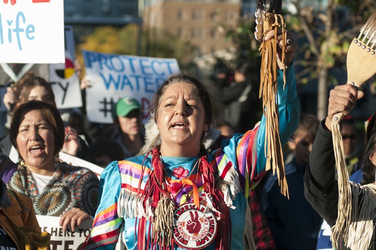 Una mujer indígena levanta el brazo mientras grita en medio de una protesta.