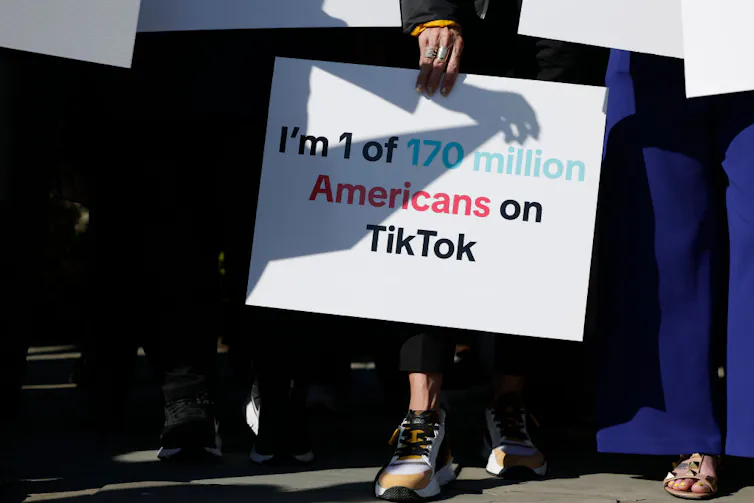 Woman holds sign reading 'I'm 1 of 170 million Americans on TikTok.'