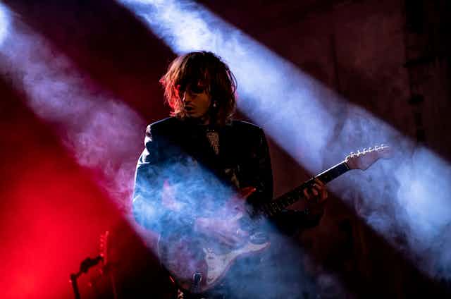 Guitar player bathed in red and blue lights and fog.