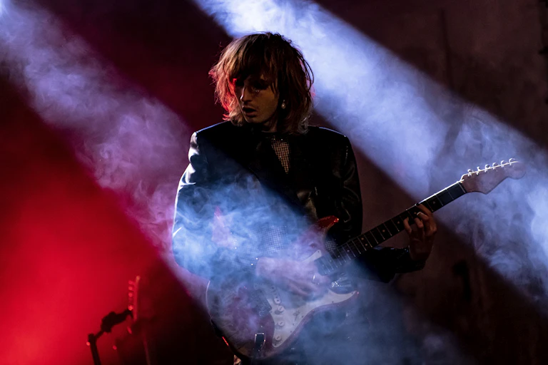 Guitar player bathed in red and blue lights and fog.