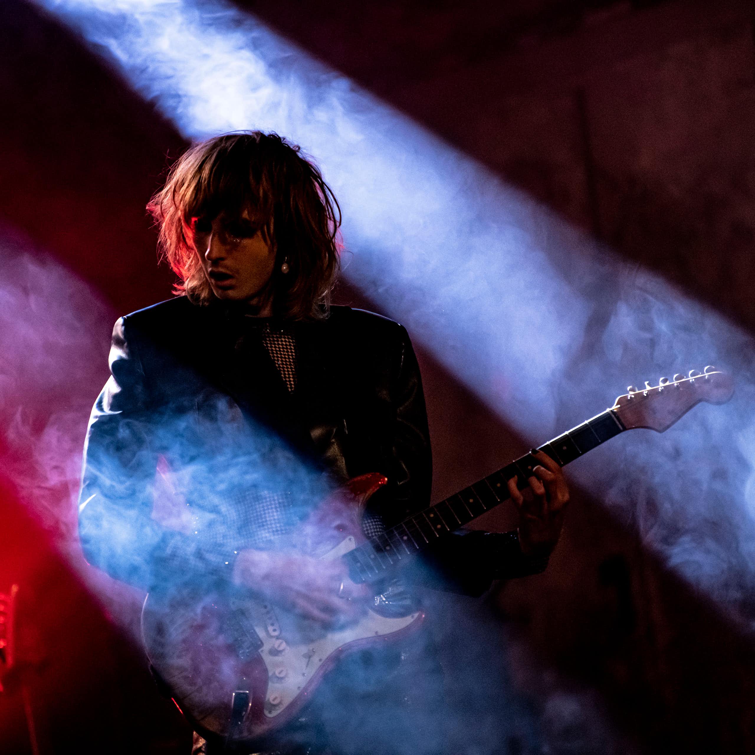 Guitar player bathed in red and blue lights and fog.