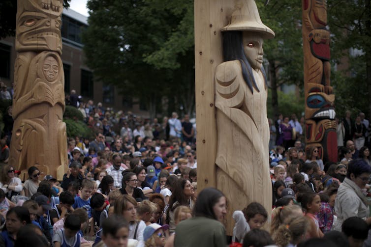 People seen standing in a crowd among carvings.