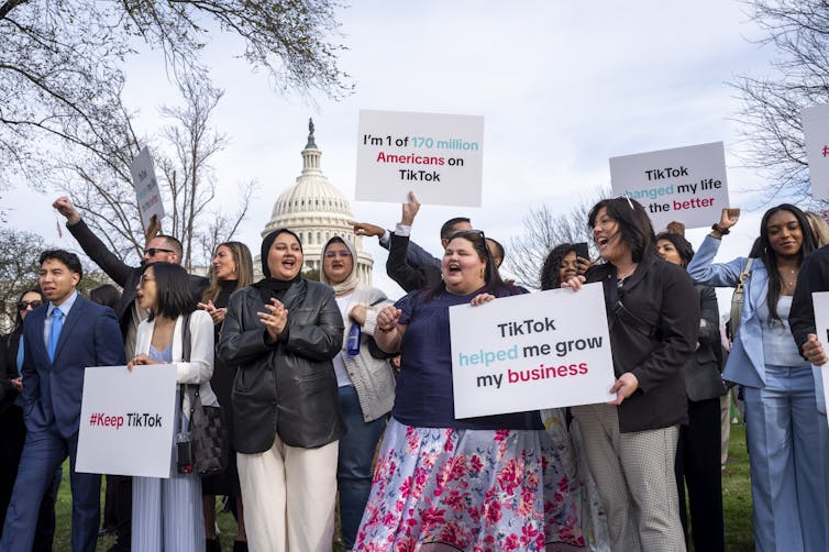 a group of people protesting with signs that read I'M ONE OF 170 MILLION AMERICANS WHO USE TIKTOK. the US capitol can be seen in the background