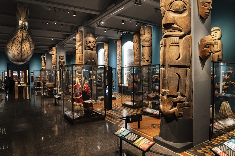 A series of totem poles and other Indigenous artifacts on display in a museum