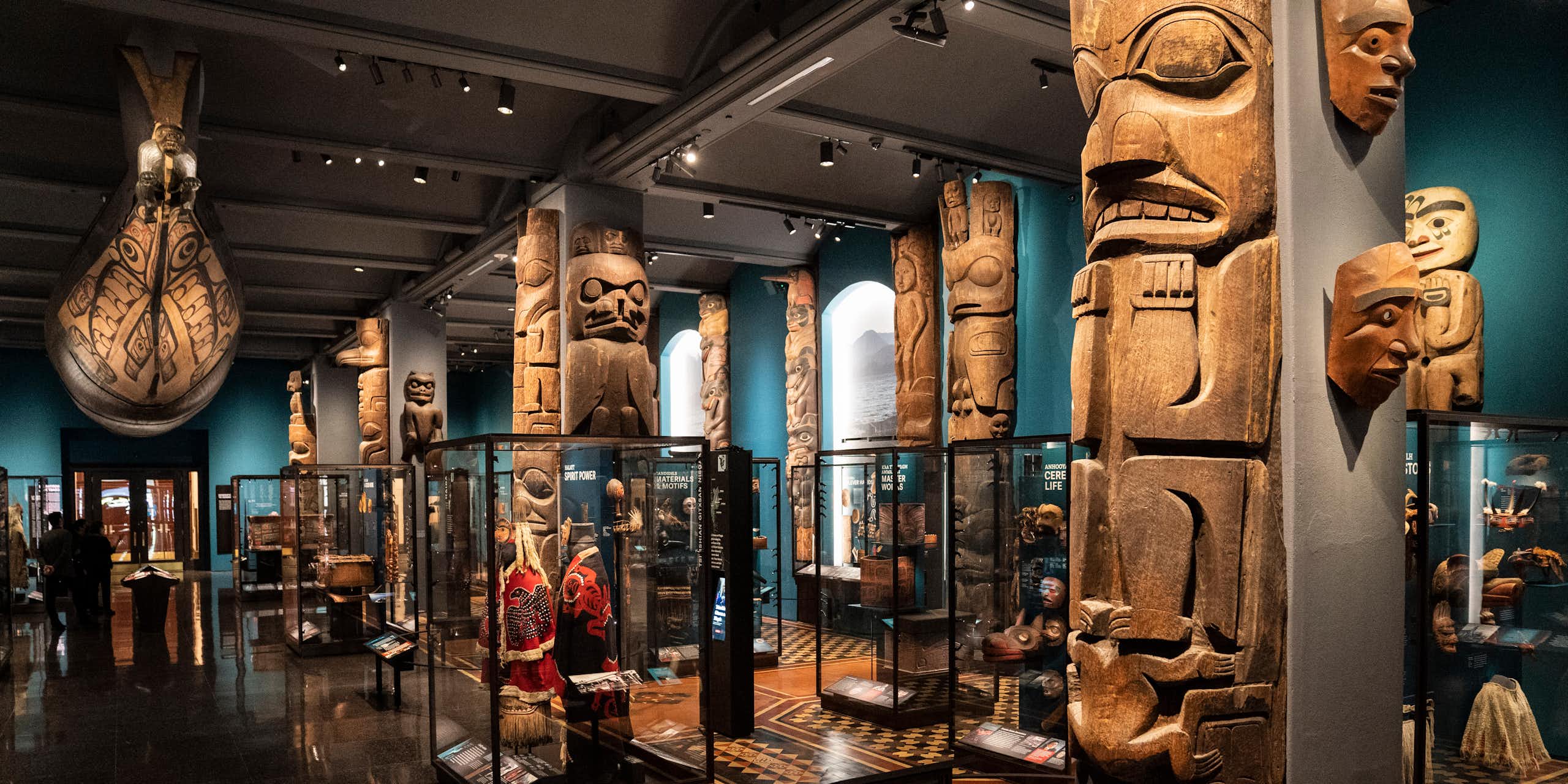 A series of totem poles and other Indigenous artifacts on display in a museum