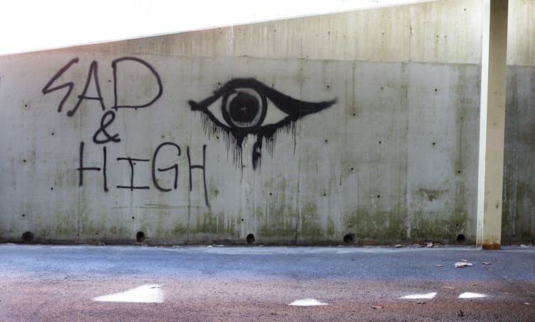 Graffiti reading 'SAD & HIGH' next to a teary eye.