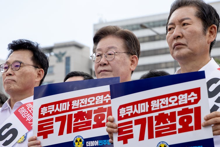 South Korean opposition party members hold signs at a rally.