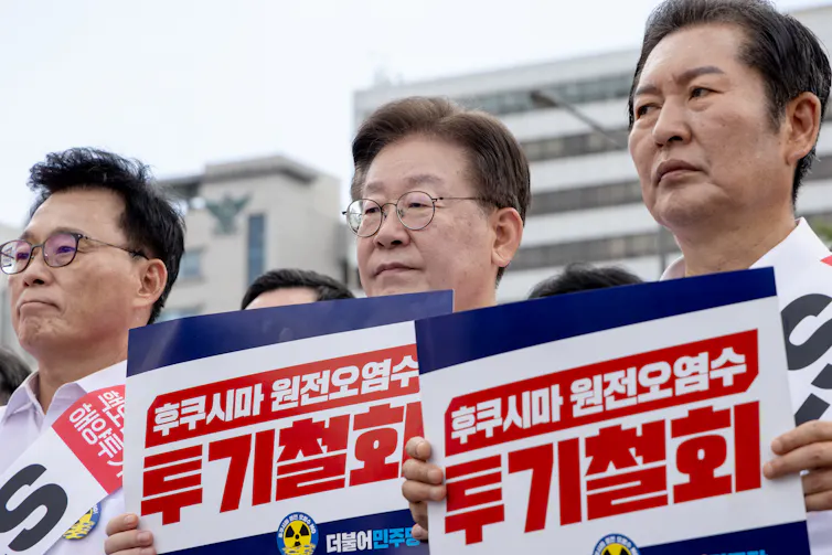 South Korean opposition party members hold signs at a rally.