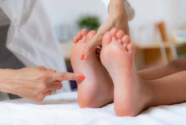 Un pédiatre examine les pieds d’un garçon en développement sur un lit.