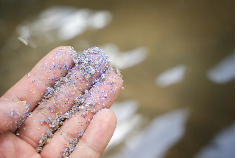 A hand with microplastics on it.