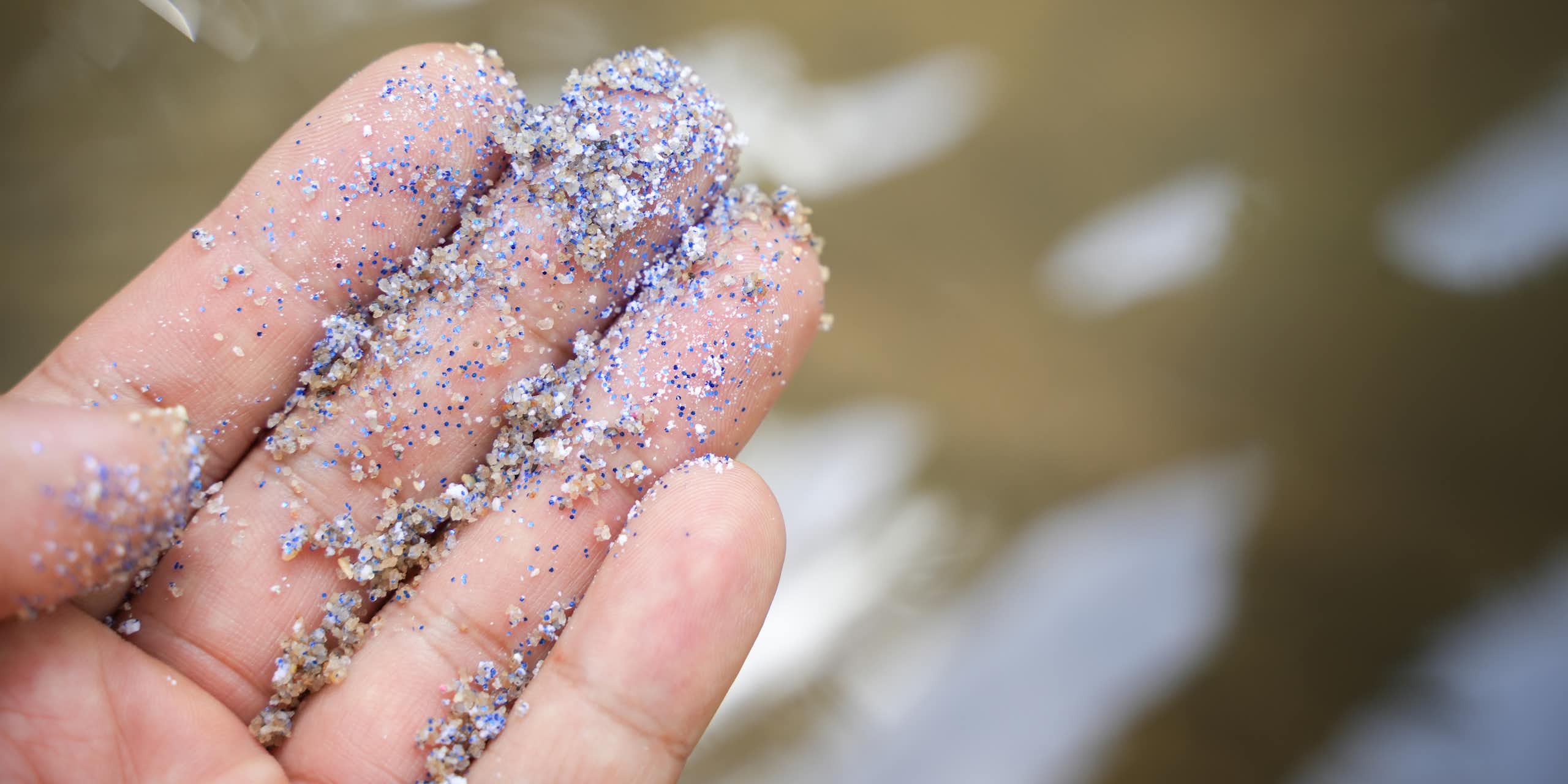 A hand with microplastics on it.