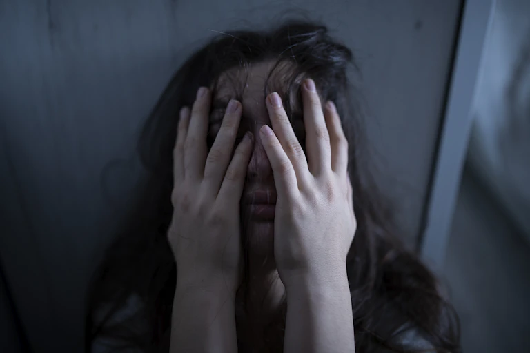Young woman with hands over face