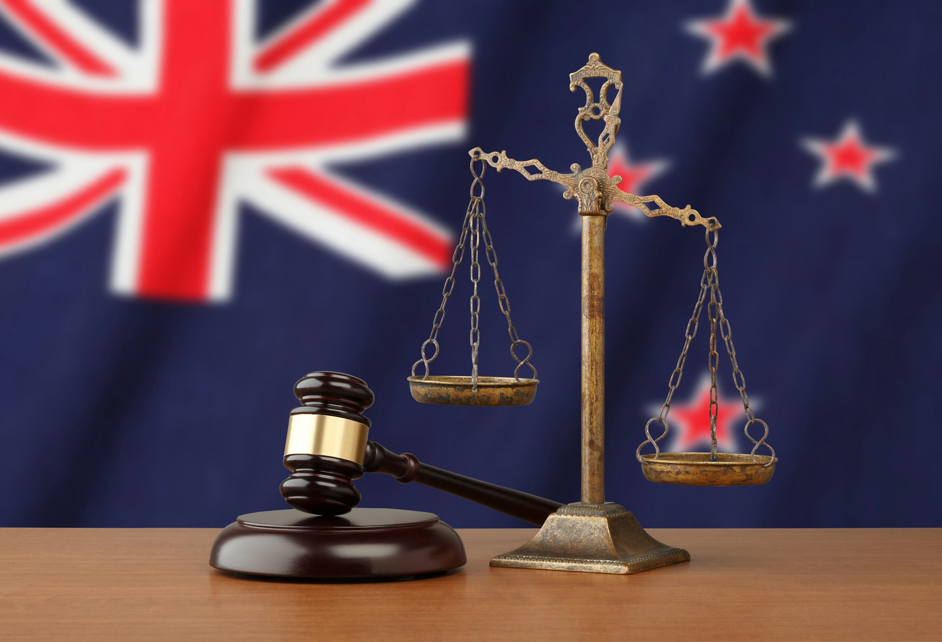 scales of justice and gavel in front of New Zealand flag.