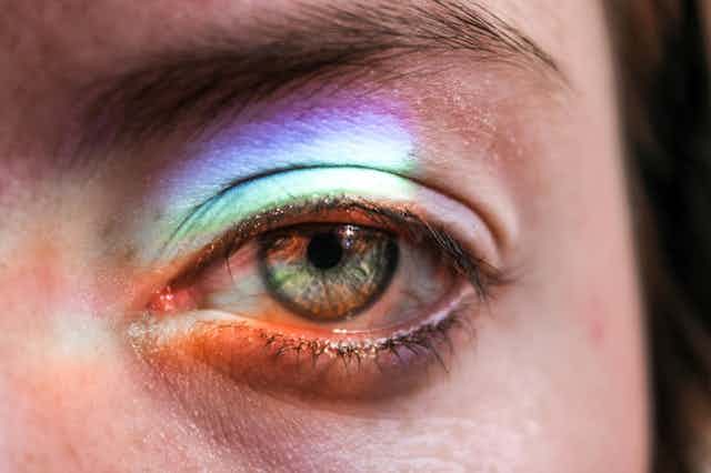 person's eye in close up with rainbow of light cast on it