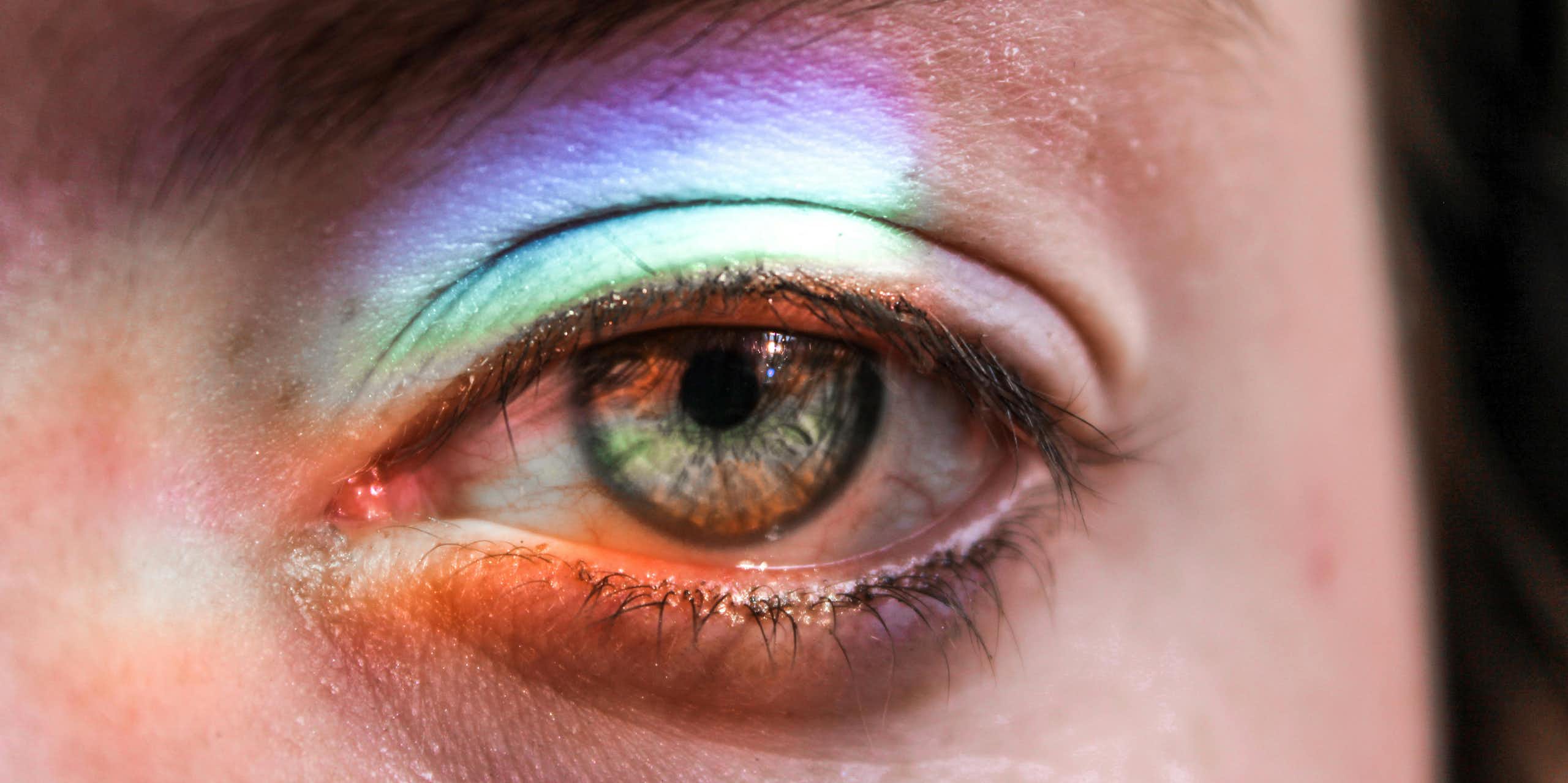 person's eye in close up with rainbow of light cast on it