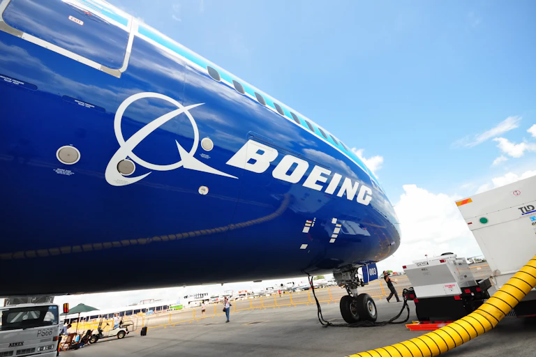 Un avion bleu foncé avec le logo Boeing sur un tarmac en train d'être ravitaillé en carburant.