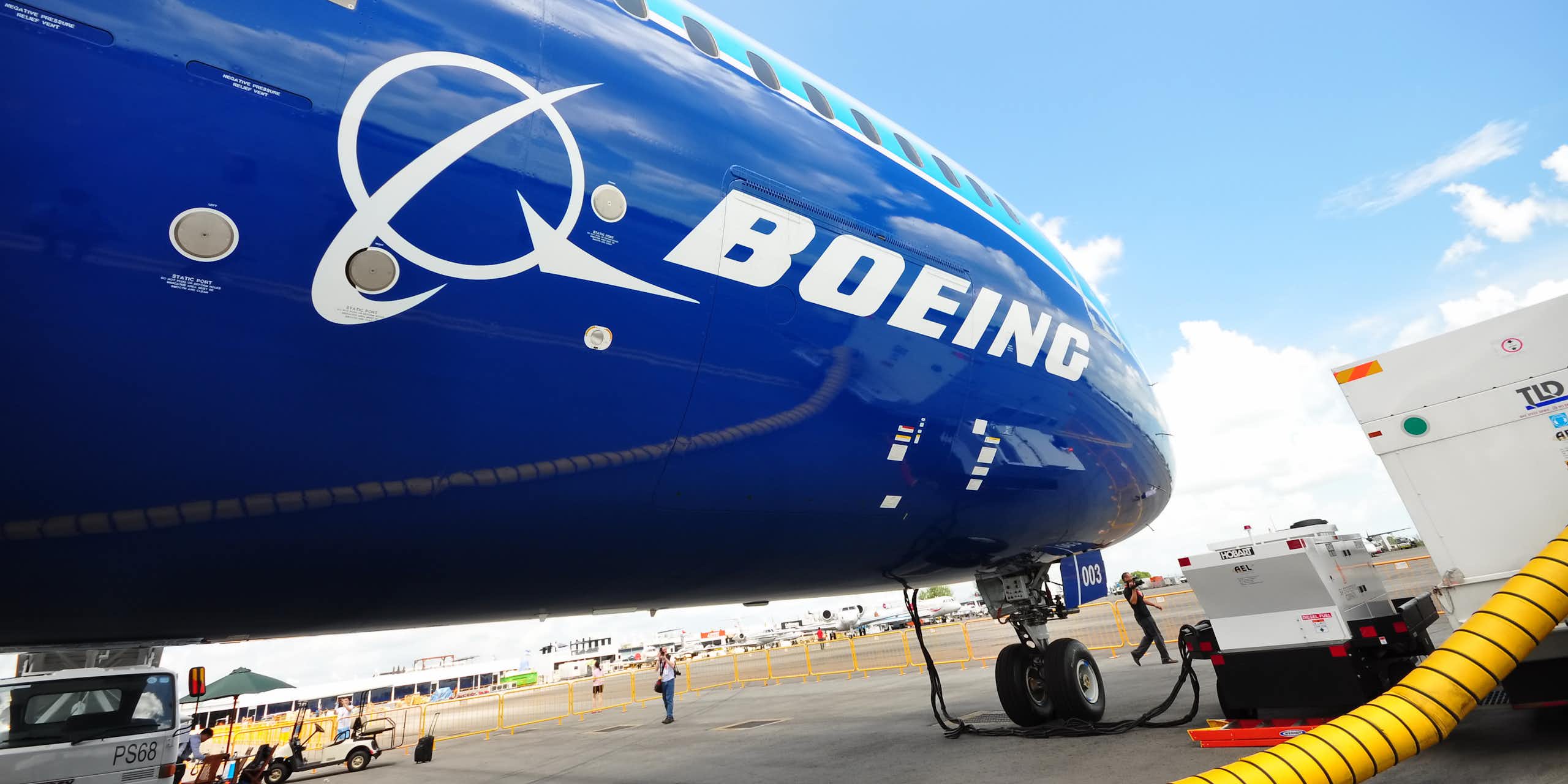 Un avion bleu foncé avec le logo Boeing sur un tarmac en train d'être ravitaillé en carburant.