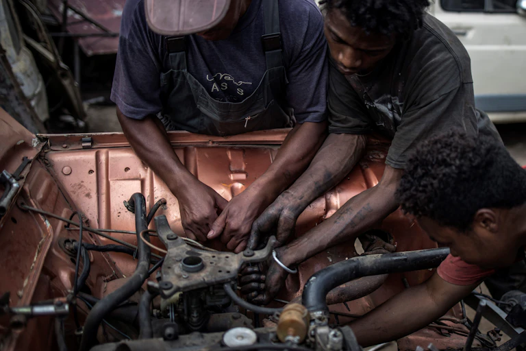 Young mechanics work on the engine of a car.