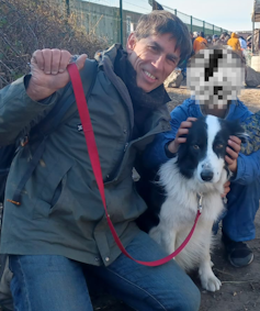 Man posing with dog and child. Child's faced blurred out so as not to identify them.