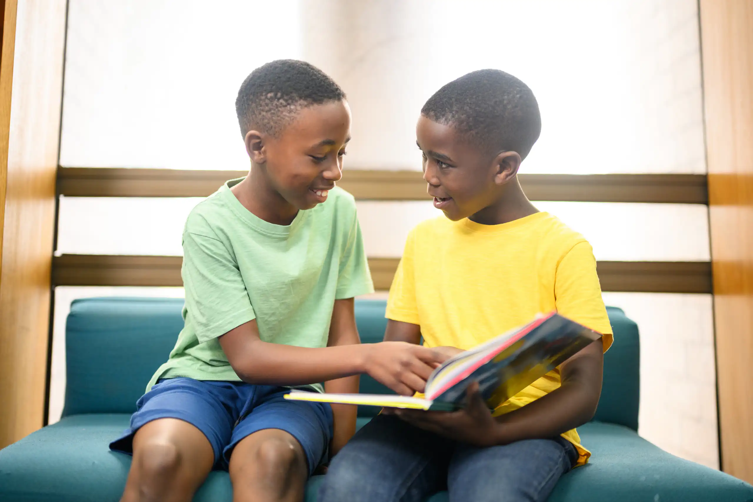 Two boys talking with a book in front of them