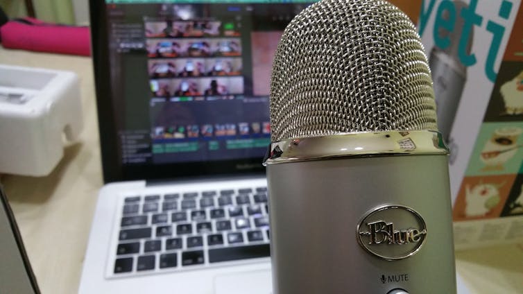 A microphone seen in front of a computer screen showing videoconferencing.