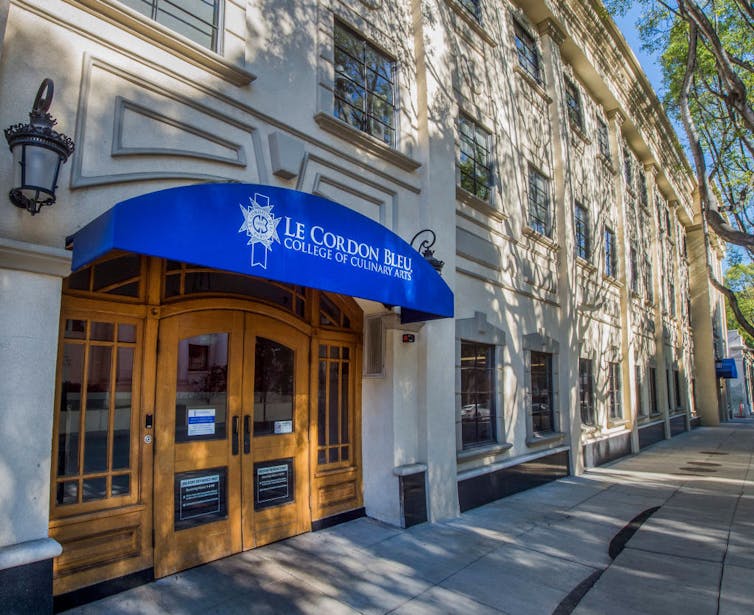 Blue awning hanging over entrance to three story building reads 'Le Cordon Bleu College of Culinary Arts.'