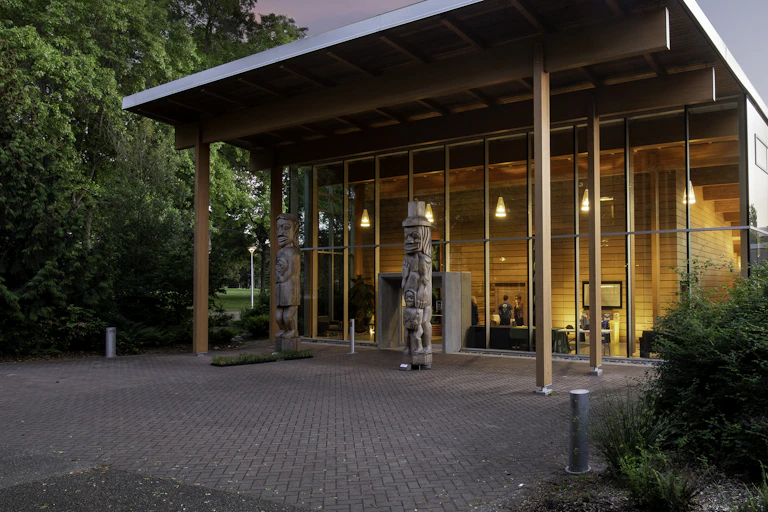 A building seen with a glass front and totem poles in the front.