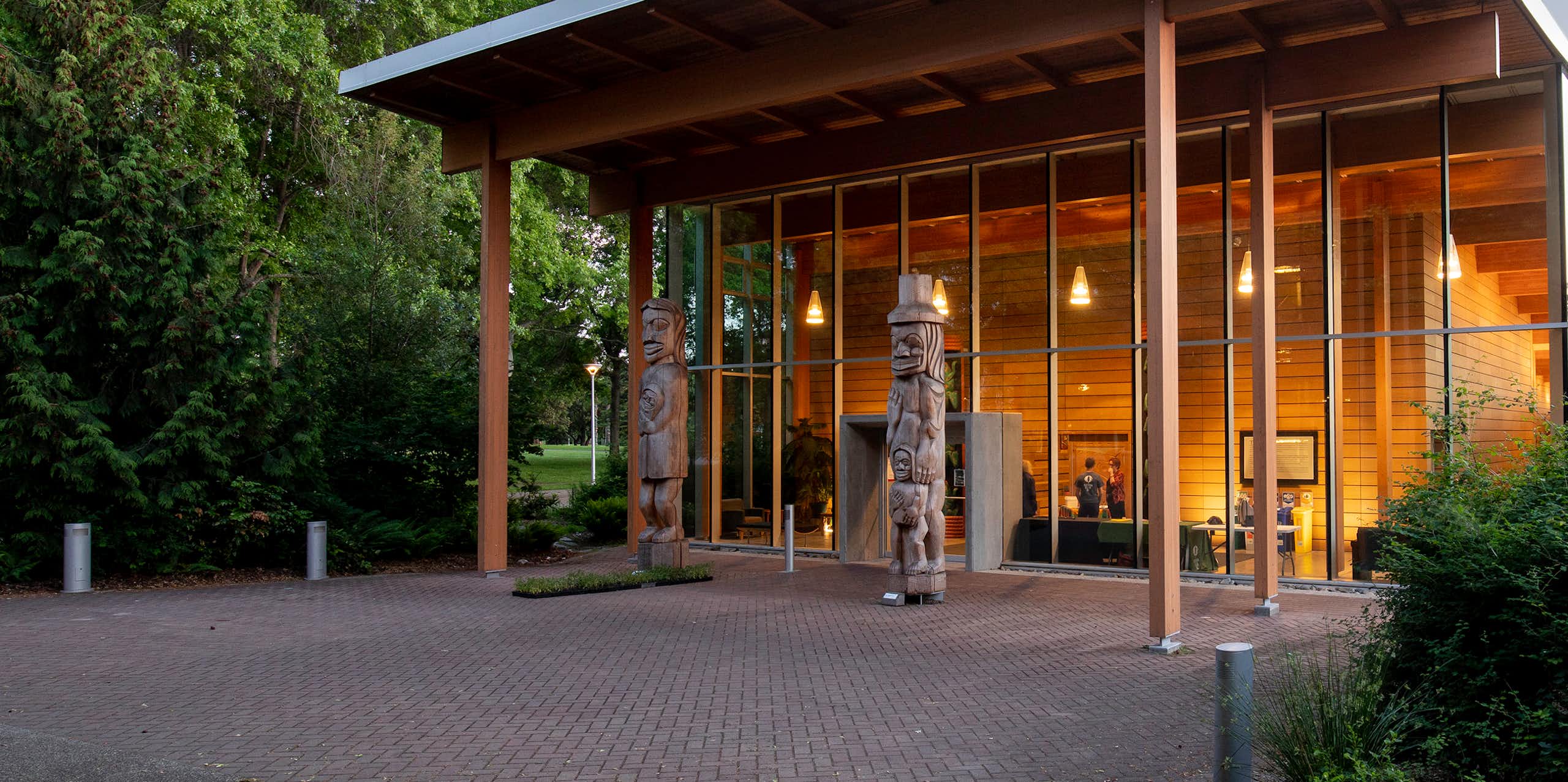 A building seen with a glass front and totem poles in the front.
