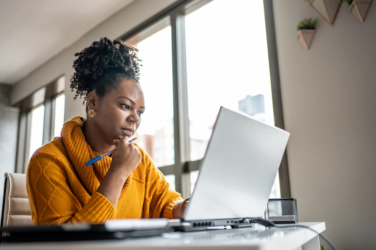 A woman works on a laptop in her home.