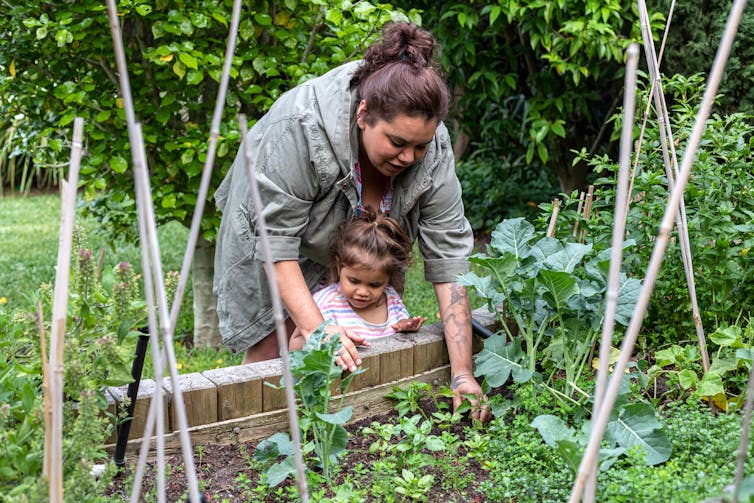 Kinship carer shows child the veggie patch
