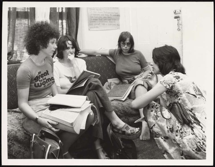 A group of women on the couch in the 1970s, talking and holding books