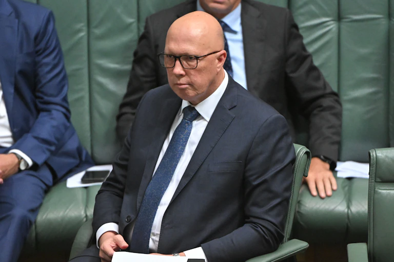 A man in a suit sits in a seat in the House of Representatives