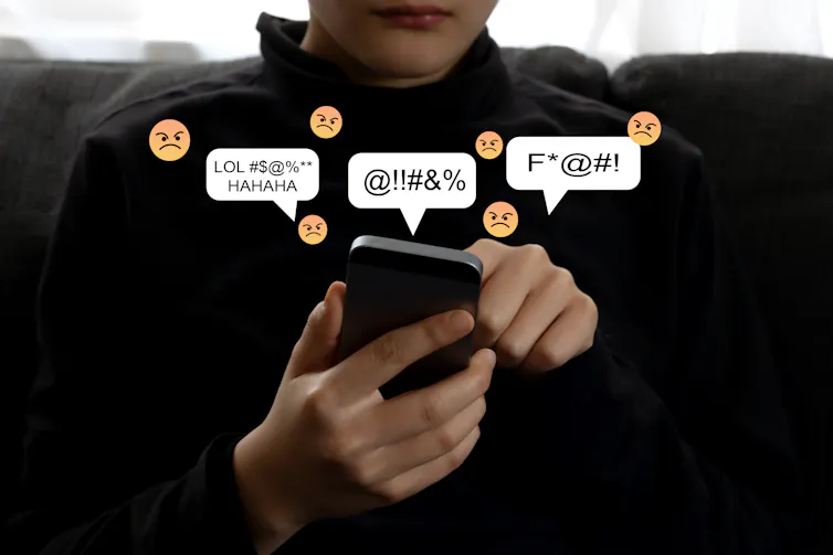 Un adolescent est sur son smartphone dont sortent des émoticônes et signes négatifs.