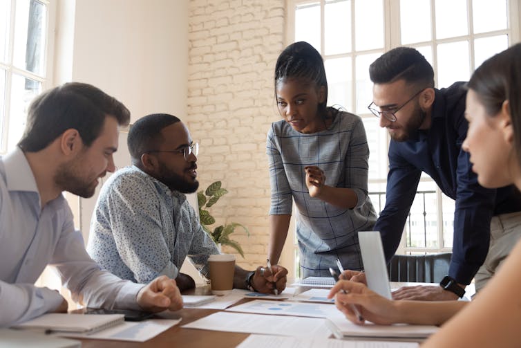 A group of ethnically diverse people having a conversation around a conference table