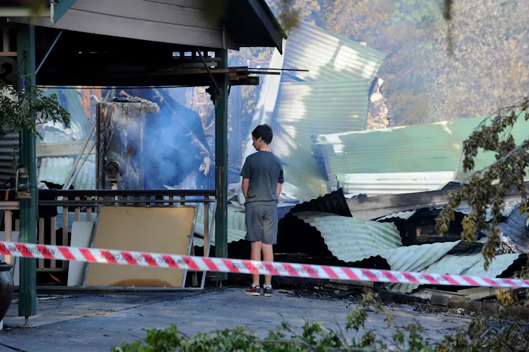 boy looks at fire-damaged home
