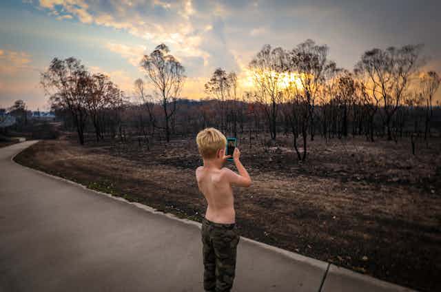 boy takes photo of fire-ravaged land
