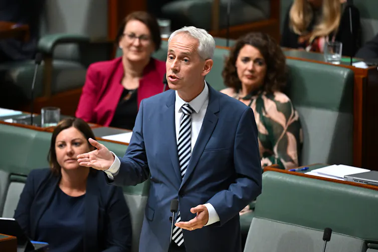 A man in a suit stands and speaks in the house of representatives