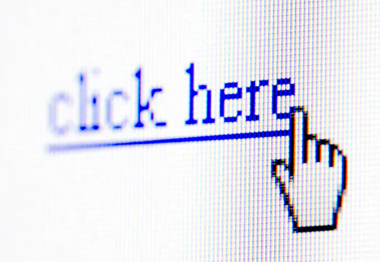 Close-up of a mouse cursor hovering over a click here link on a computer screen.