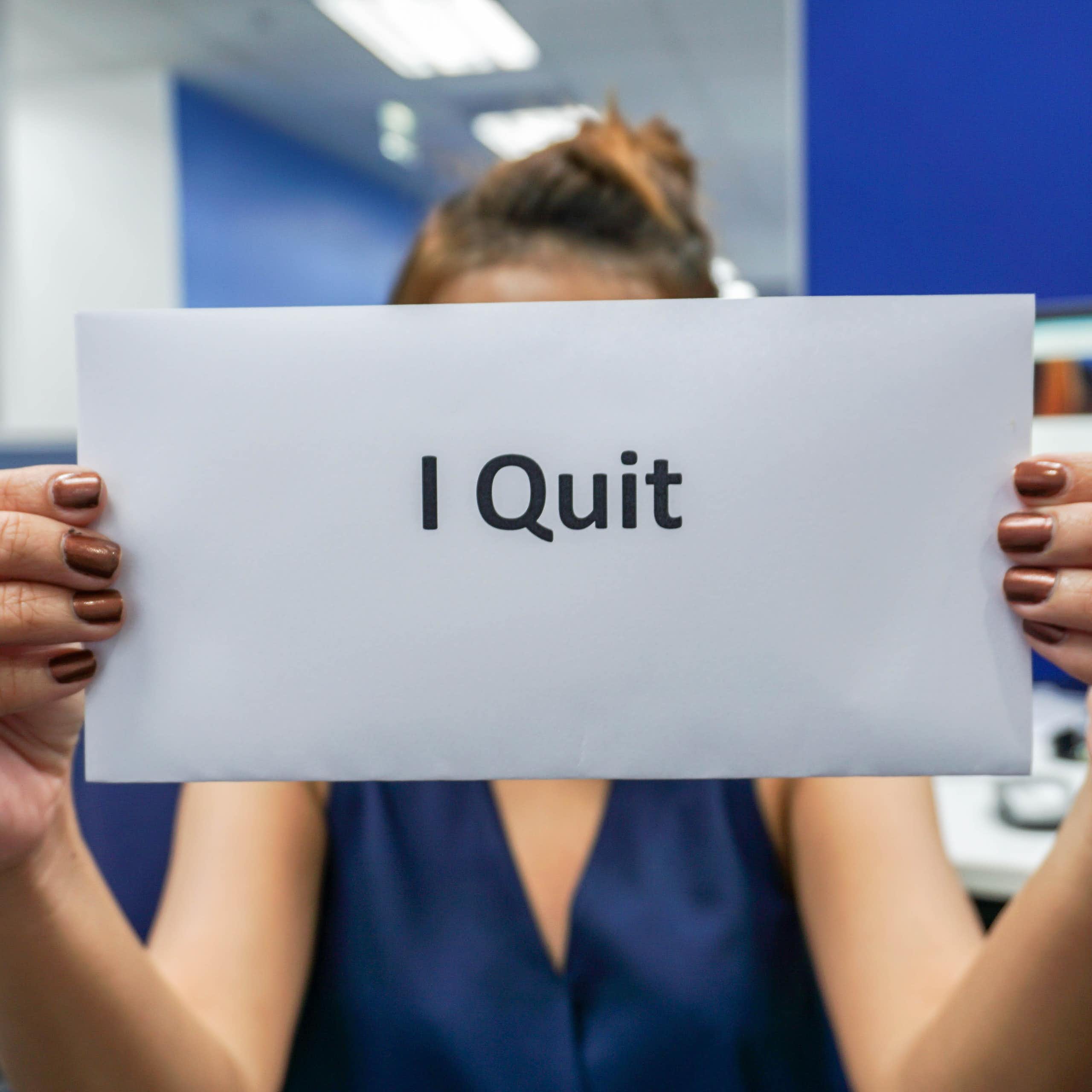 Woman holding up envelope with 'I Quit' on it. 