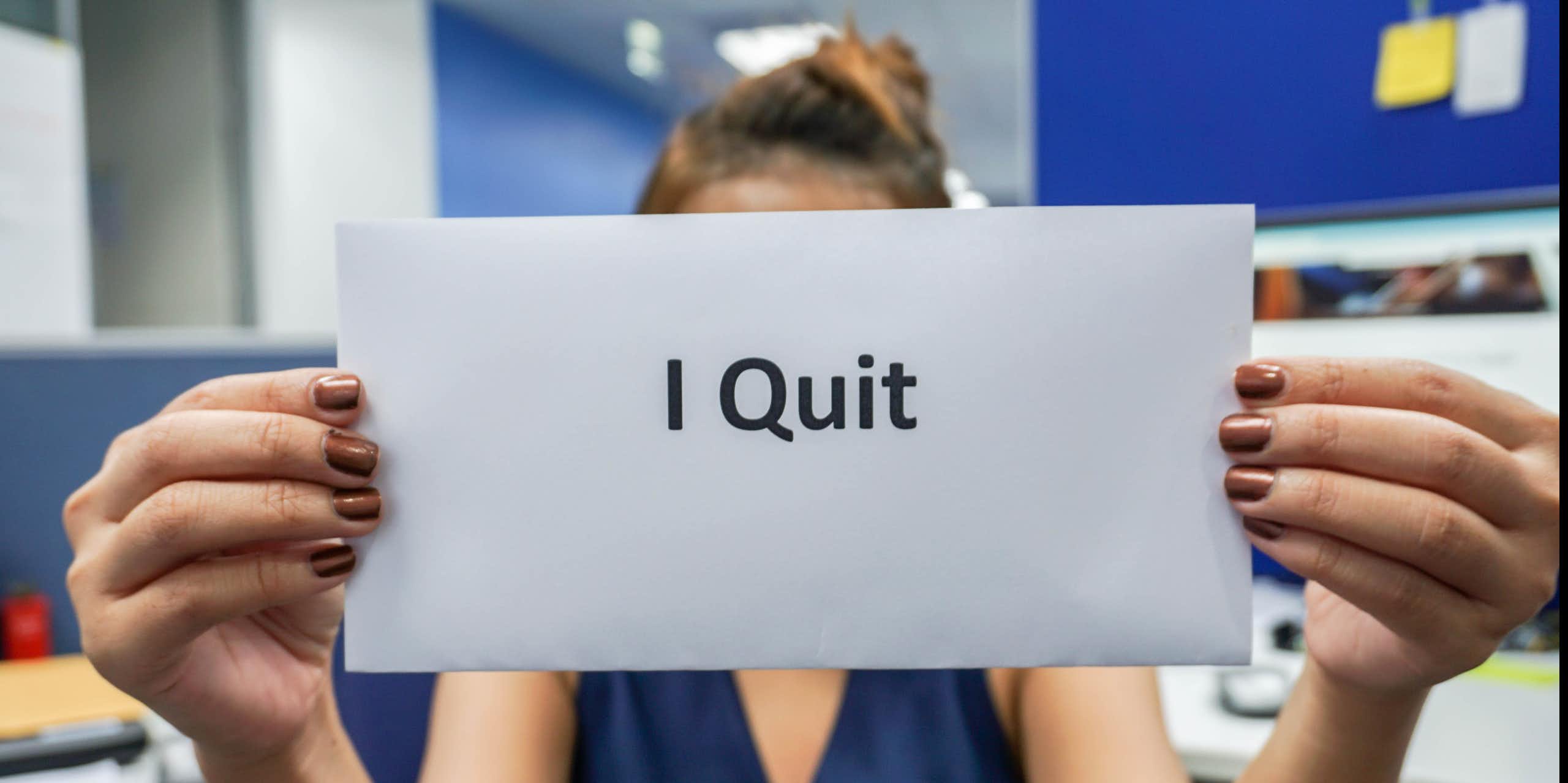 Woman holding up envelope with 'I Quit' on it. 